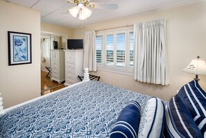 Ein Schlafzimmer mit einem Bett, einem Fernseher, einem Schreibtisch und einem Sessel.