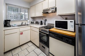 Eine kleine Küche mit Herd, Mikrowelle, Backofen und Kühlschrank.
