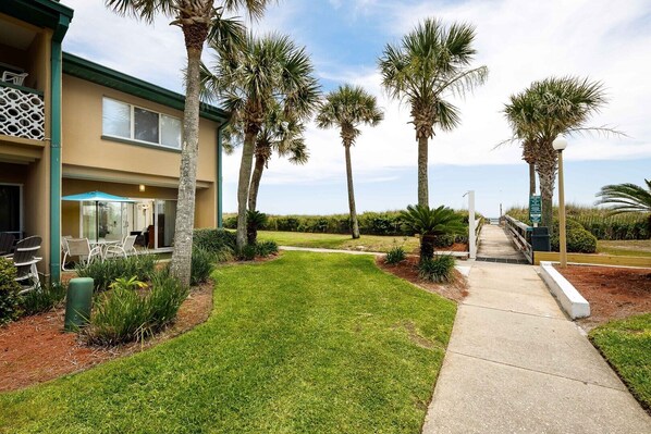 A hotel with a well-maintained lawn, palm trees, and a patio area with outdoor seating.