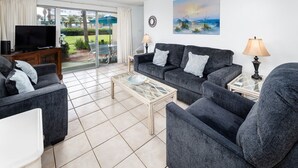 Un salon comprenant un canapé, une table basse, un téléviseur et un tableau accroché au mur.