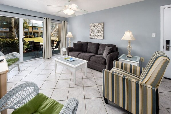 A living room with a sofa, armchairs, a coffee table, and a ceiling fan.
