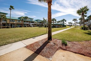 A hotel with a green roof, palm trees, and a clear sky. - Seaspray Condos - 204A (Fort Walton Beach)