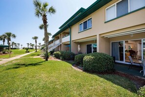 A multi-story hotel with balconies, a covered patio, and a well-maintained lawn.
