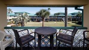 An outdoor patio with wicker furniture and a view of a hotel complex. - Seaspray Condos - 204C (Fort Walton Beach)