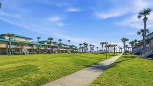 Un hotel con techo verde, palmeras y cielo despejado.