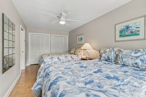 Une chambre à coucher avec un lit, un ventilateur de plafond, une table de chevet, une lampe et un tableau encadré au mur.
