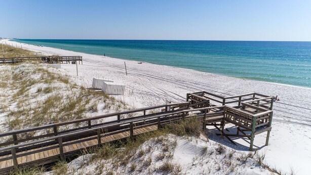 A beach with wooden boardwalks leading to a sandy area and a wooden structure. - Seaspray Condos - 206A (Fort Walton Beach)