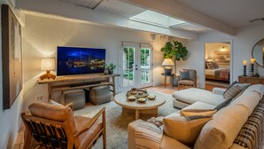 A living room with a television, sofa, coffee table, and a dining area with a table and chairs. - Casa Paradiso: Private Montecito Garden Estate (Santa Barbara)