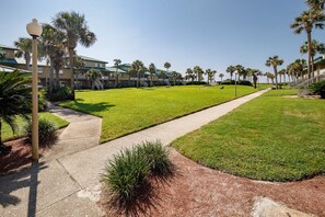 A well-maintained lawn with a pathway leading to a building complex with multiple balconies.