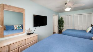 A bedroom with two beds, a TV, a dresser, and a ceiling fan.