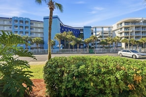 A hotel with multiple floors, a parking area, and a white car parked in front.