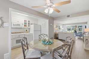 A modern kitchen with white cabinets, a dining table with chairs, and a ceiling fan.