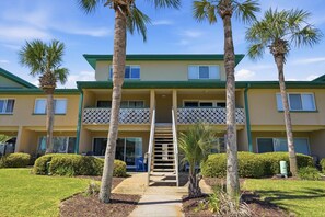 A two-story building with a central staircase, surrounded by palm trees and a well-maintained lawn. - Seaspray Condos - 212B (Fort Walton Beach)