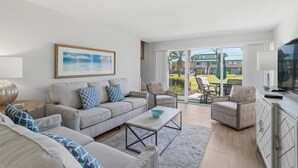 Una sala de estar moderna con un sofá, sillones, una mesa de centro y un televisor.