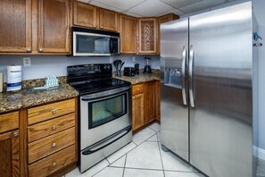 Una cocina con armarios de madera, un refrigerador de acero inoxidable, un microondas y una estufa.