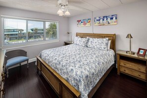 Un dormitorio con cama, una silla, una mesita de noche y una ventana con persianas.