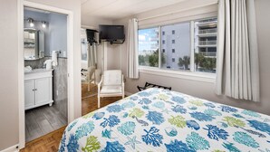Une chambre à coucher avec un lit, un téléviseur, une chaise et une vue sur les bâtiments environnants.
