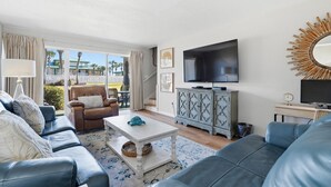 A living room with a sofa, armchair, coffee table, TV, and a cabinet. - Seaspray Condos - 215B (Fort Walton Beach)