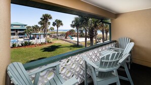 A balcony with a view of a pool, palm trees, and a beach. - Seaspray Condos - 216C (Fort Walton Beach)