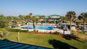 A resort with a swimming pool surrounded by palm trees and lounge chairs. - Seaspray Condos - 216C (Fort Walton Beach)