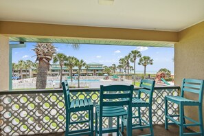 Een balkon met stoelen, een zwembad en uitzicht op een resort.
