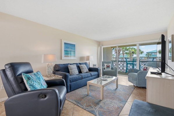 Una sala de estar con sofá, sillón, mesa de centro y televisor.