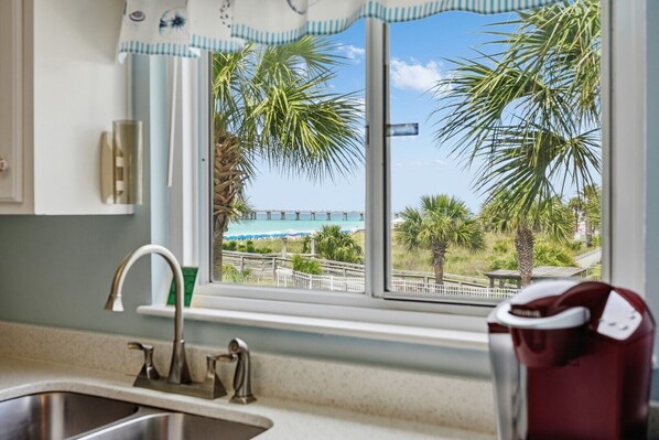 Una cocina con ventana que da a una playa y un muelle.