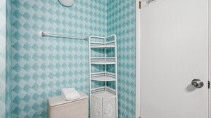 Une salle de bain avec un mur à motifs, un lavabo blanc, une serviette et une étagère blanche.