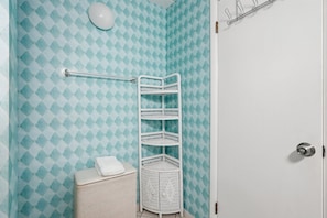 Un baño con una pared estampada, un lavamanos blanco, una toalla y un estante blanco.