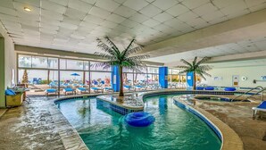 Une piscine intérieure dotée de chaises longues et de palmiers.