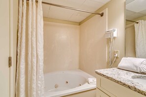 Ein Badezimmer mit einer Badewanne, einem Handtuch, einem Föhn und einem Spiegel.