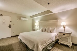 Ein Hotelzimmer mit einem großen Bett, Nachttischen, einer Klimaanlage und einer Tür mit Schloss.