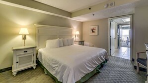 A hotel room with a large bed, two bedside tables with lamps, a small desk, and a view of the balcony. - · Oceanfront King Jacuzzi Suite - Beautiful Views! (Myrtle Beach)