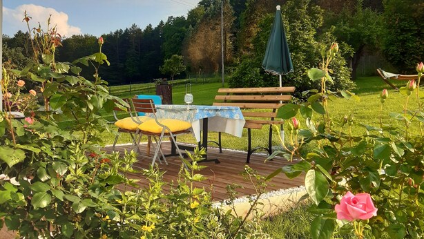 A garden with a wooden bench, a table with a yellow cushion, and a butterfly decoration.