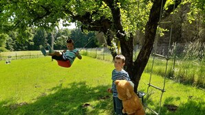 A grassy outdoor area with a swing set and a tree.