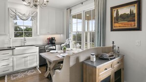 A kitchen with white cabinets, a dining table, and a chandelier. - Unique hilltop home with amazing views and close to Main Street; with Pickleball (Fredericksburg)