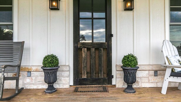 A front porch with a wooden door, two potted plants, a bench, and a chair. - Unique hilltop home with amazing views and close to Main Street; with Pickleball (Fredericksburg)