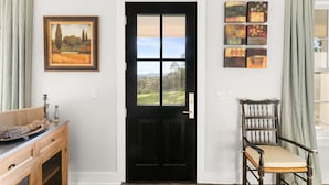A black door with a window, a wooden chair, and a painting on the wall. - Unique hilltop home with amazing views and close to Main Street; with Pickleball (Fredericksburg)