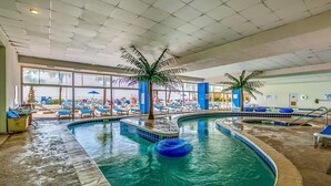 An indoor swimming pool with lounge chairs and palm trees. - · Beautiful Oceanfront Deluxe - Pool, Lazy River, Hot Tub and more! (Myrtle Beach)