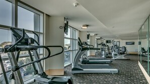 A gym with treadmills, elliptical machines, and weight equipment, large windows, and a view of the city. - · Beautiful Oceanfront Deluxe - Pool, Lazy River, Hot Tub and more! (Myrtle Beach)