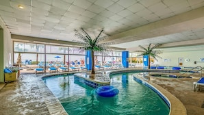 Una piscina interior con sillas de descanso y palmeras.