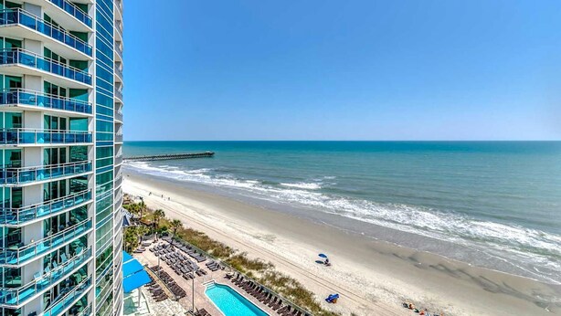 Een hoog hotel met zwembad en uitzicht op het strand.