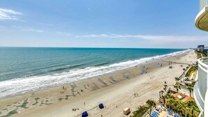 A beach with a clear view of the ocean, a sandy shore, and a building with balconies overlooking the beach. - · Gorgeous 3 Bedroom Condo - Pools, Lazy River, Hot Tub (Myrtle Beach)