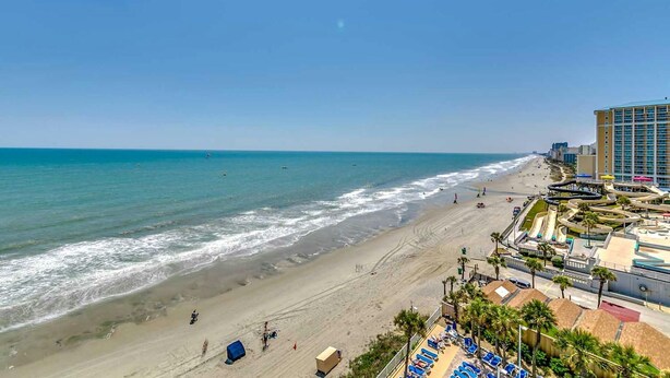 A beach with a water slide and a hotel in the background. - · Luxury Oceanfront 2Bdrm Condo - Free Wifi, Pool, Hot Tub, Lazy River! (Myrtle Beach)