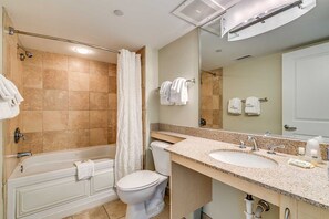 Une salle de bain avec une baignoire, des toilettes et deux lavabos avec miroirs.