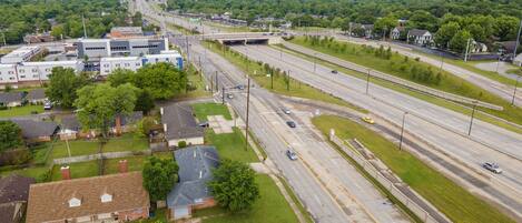 An aerial view of a highway interchange with multiple lanes, surrounded by residential areas and greenery.