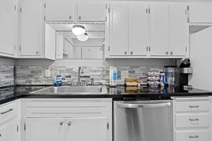 A kitchen with white cabinets, a stainless steel dishwasher, a granite countertop, and a backsplash with gray tiles. - Great Place to Stay, Near all Tulsa Attractions (Tulsa)