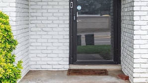 A white brick building with a black door and a small step leading up to the entrance.