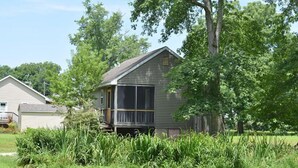 Uma casa de dois andares com varanda, rodeada por vegetação exuberante e árvores.