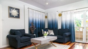 A living room with two dark sofas, a light-colored coffee table, and a decorative wall piece. - Luxury Home away from Home (Georgetown)